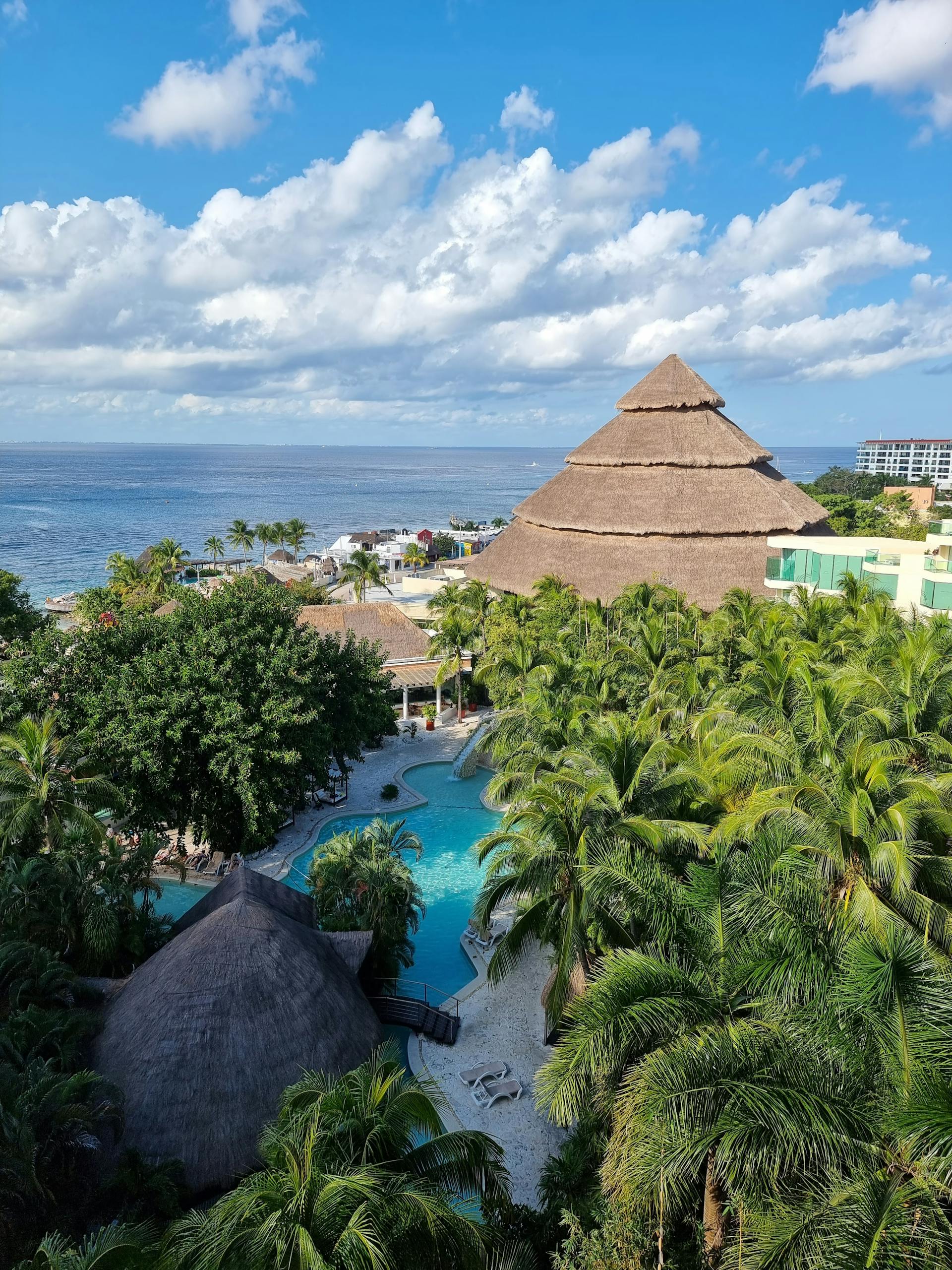 A stunning aerial view of a tropical resort in San Miguel de Cozumel, featuring lush greenery and ocean views.
