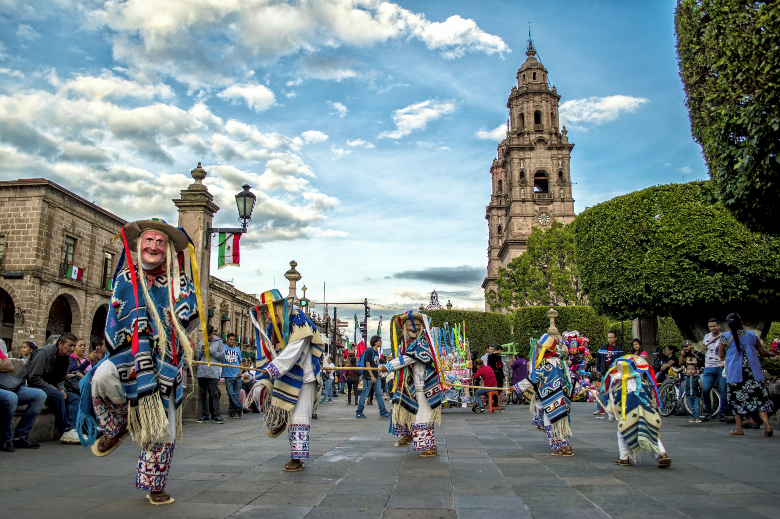Colorful traditional dance performance at a Mexican festival in front of a historic church.